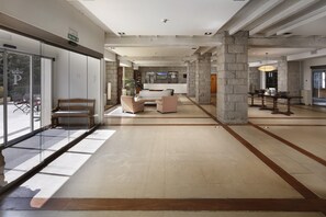 A spacious lobby with a large seating area, stone pillars, and a view through glass doors. - Parador De Vielha Spa & Wellness (Vielha e Mijaran)