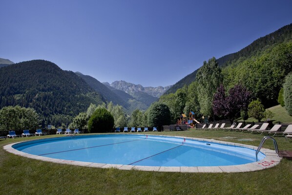 A swimming pool with lounge chairs and a mountain backdrop. - Parador De Vielha Spa & Wellness (Vielha e Mijaran)