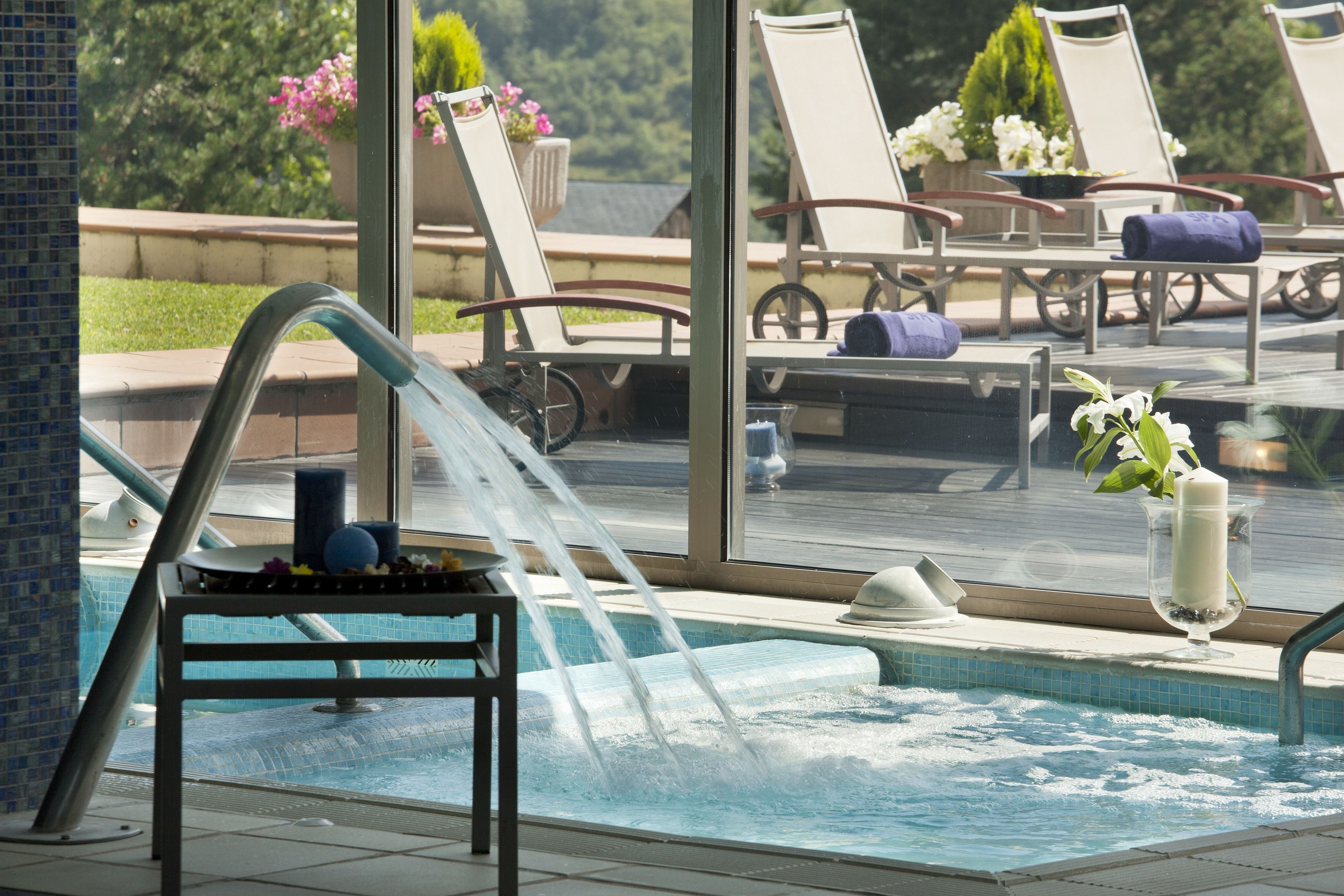 A pool area with lounge chairs and a hot tub.