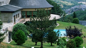 A house with a conical roof, a stone tower, and a pool. - Parador De Vielha Spa & Wellness (Vielha e Mijaran)