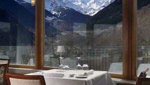 A dining area with a mountain view, tables set with white tablecloths, and chairs. - Parador De Vielha Spa & Wellness (Vielha e Mijaran)