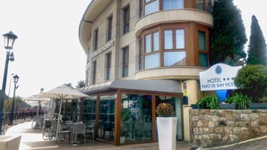 A hotel with a cafe and restaurant on the ground floor, outdoor seating, and a stone wall with plants. - Faro de San Vicente (San Vicente de la Barquera)