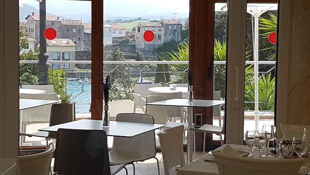 A restaurant with outdoor seating overlooking a coastal town. - Faro de San Vicente (San Vicente de la Barquera)