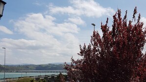 A balcony with a view of a bridge, a body of water, and distant hills. - Faro de San Vicente (San Vicente de la Barquera)