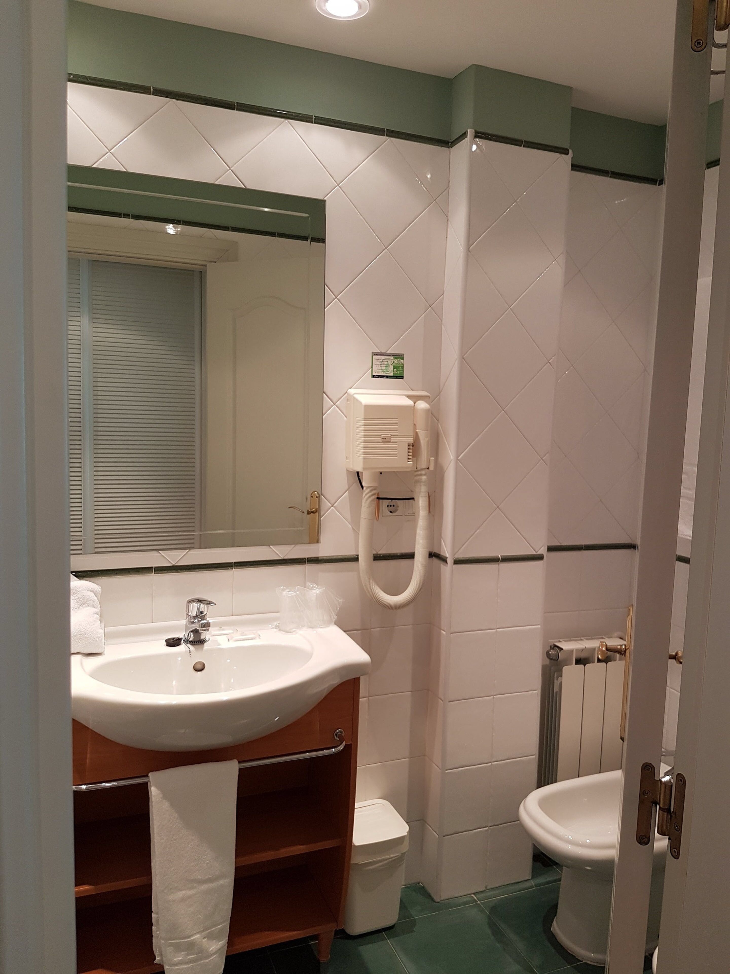 Ein Badezimmer mit Waschbecken, Spiegel, Toilette und Handtuchhalter.