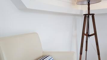 Un salón moderno con un sofá color beige, un cojín a rayas, una lámpara de pie y cuadros en la pared.
