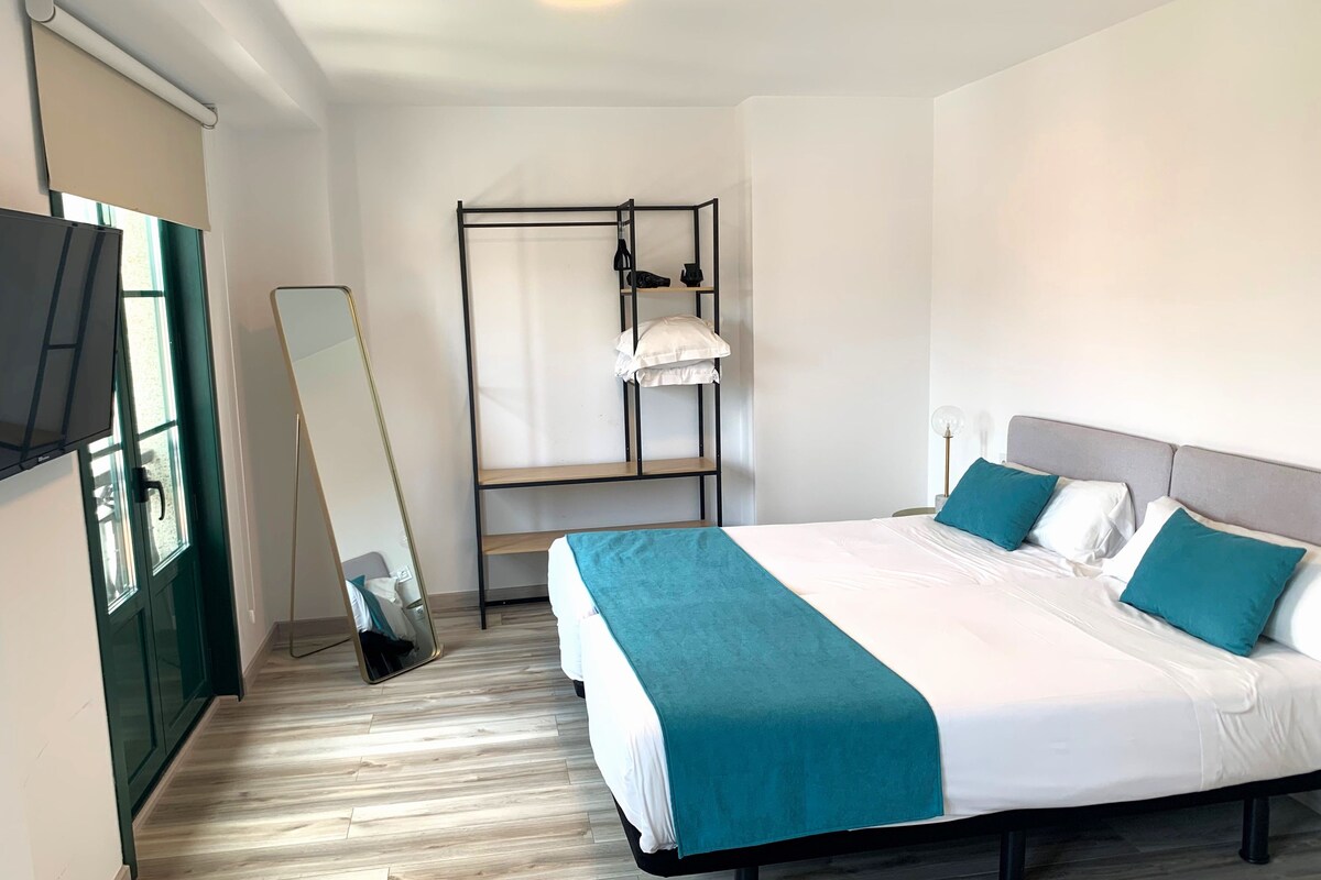 A modern bedroom with a bed, a hanging chair, a wardrobe, and a large mirror.