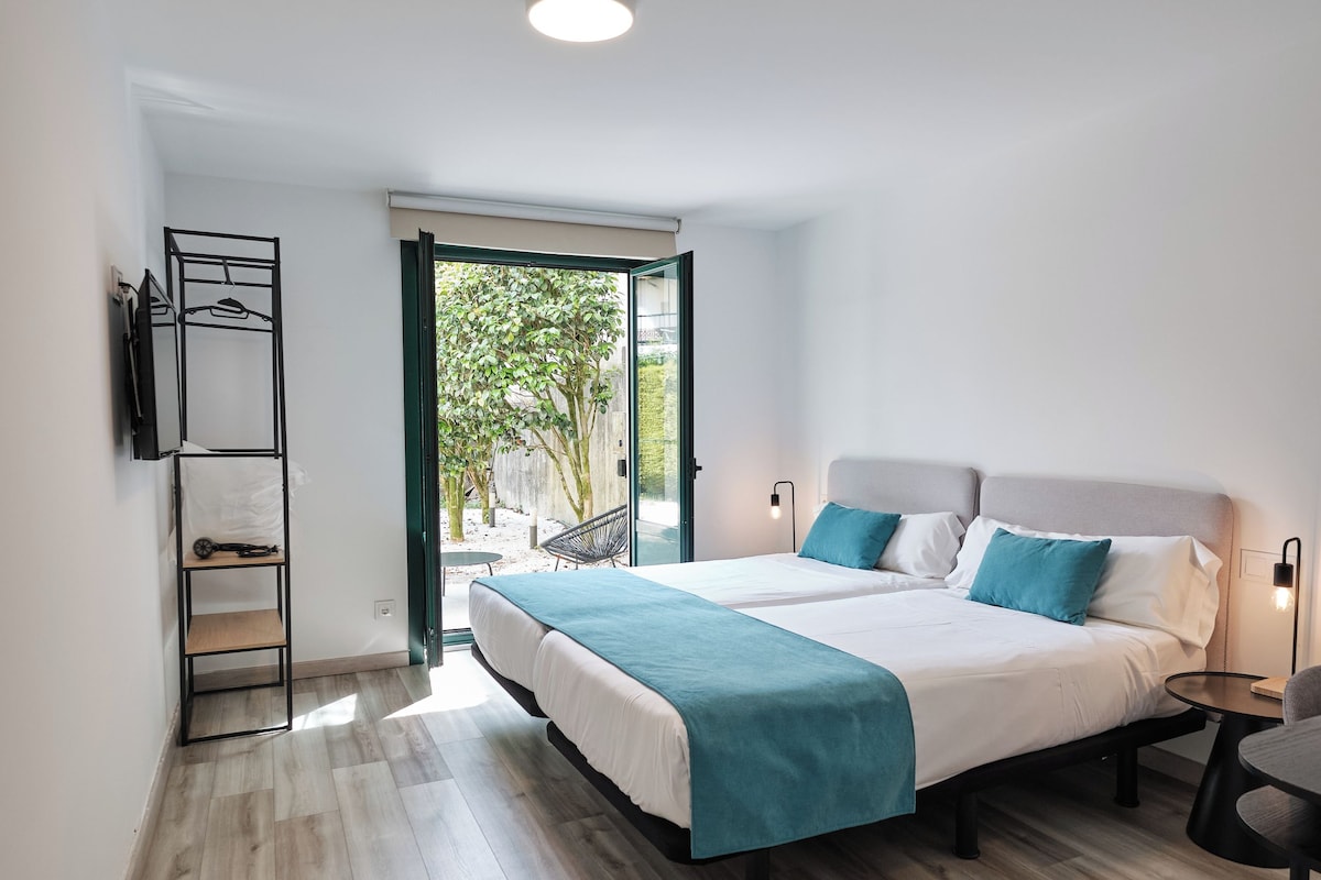 A modern bedroom with a large bed, a built-in wardrobe, and a view of the outdoors.