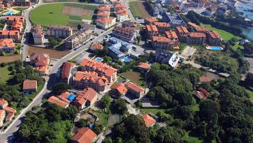 An aerial view of a residential area with multiple buildings, roads, and green spaces.