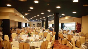 Un salón de banquetes con mesas redondas, sillas e iluminación en el techo.