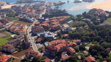 An aerial view of a coastal town with multiple buildings, a beach, and a marina.