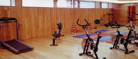 A gym with exercise equipment, wooden walls, and large windows.