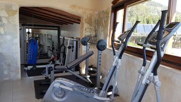 Un gimnasio con equipo cardiovascular, máquinas de pesas y un saco de boxeo.
