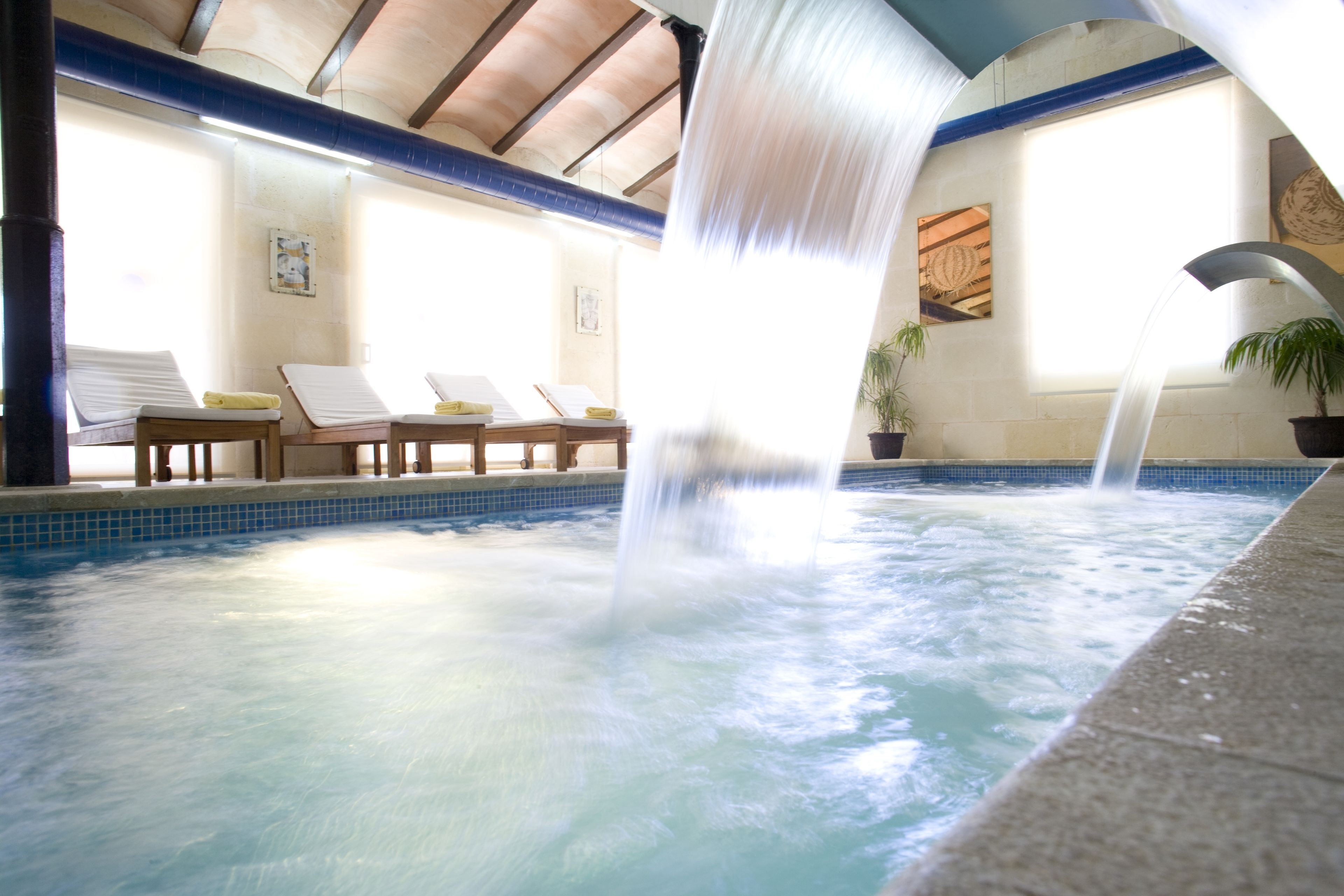 A spa area with a hot tub, lounge chairs, and a waterfall feature.