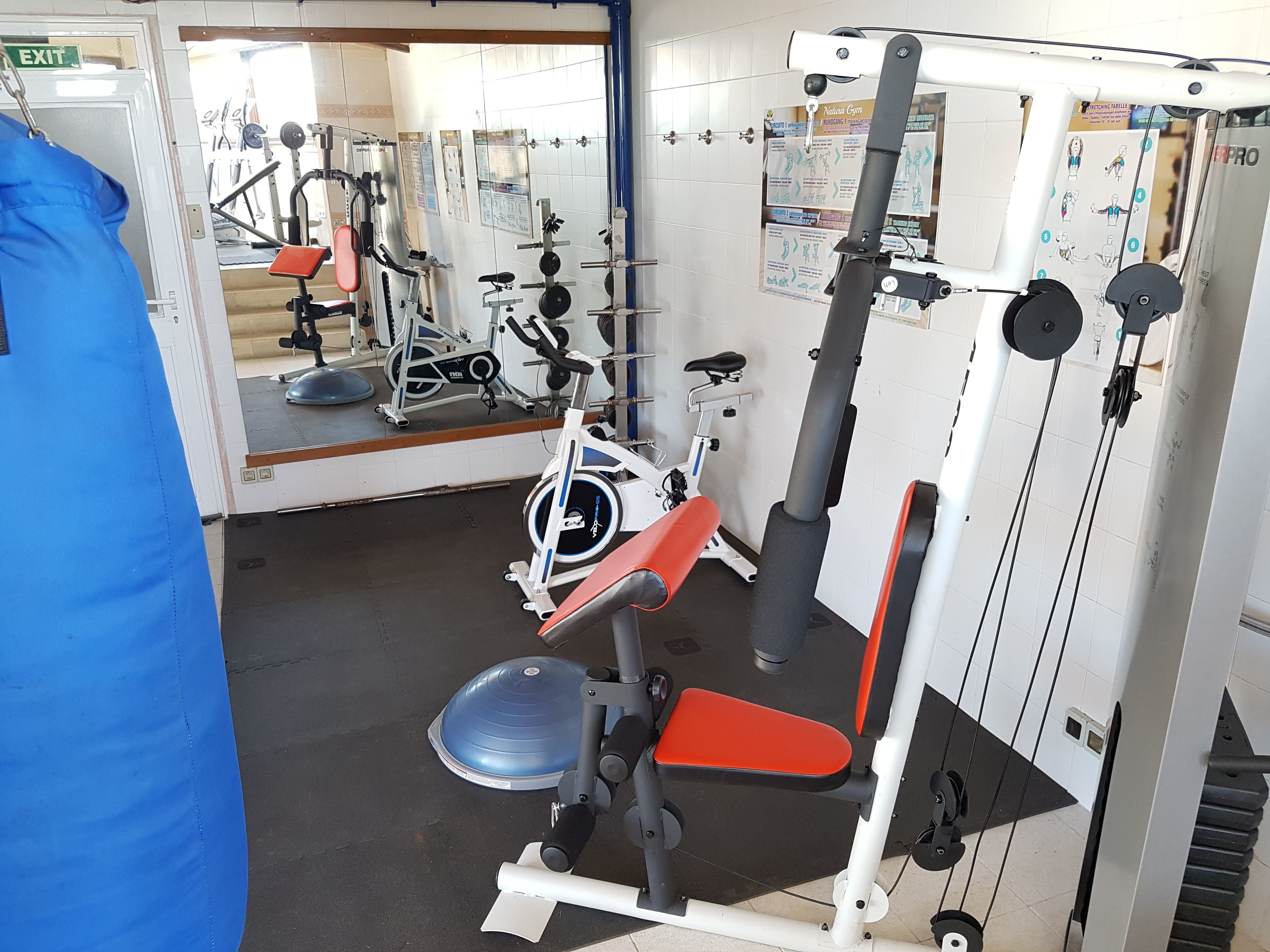 A gym with various exercise equipment, including a bench press, a rowing machine, and a stationary bike.