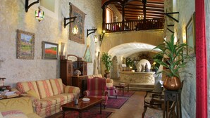 A spacious living room with a high ceiling, a balcony, and a stone fireplace.