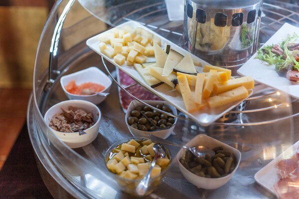A buffet table with various cheeses, olives, and meats.