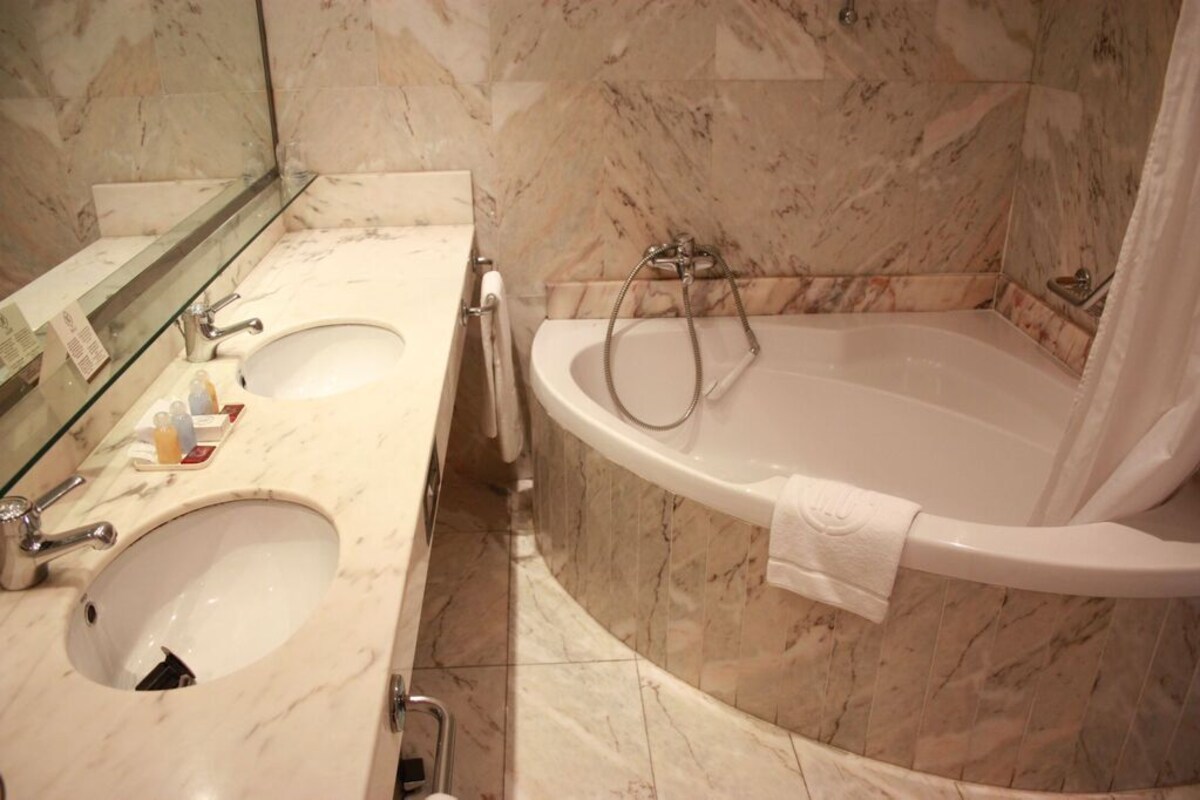 A bathroom with two sinks, a bathtub, and a shower.