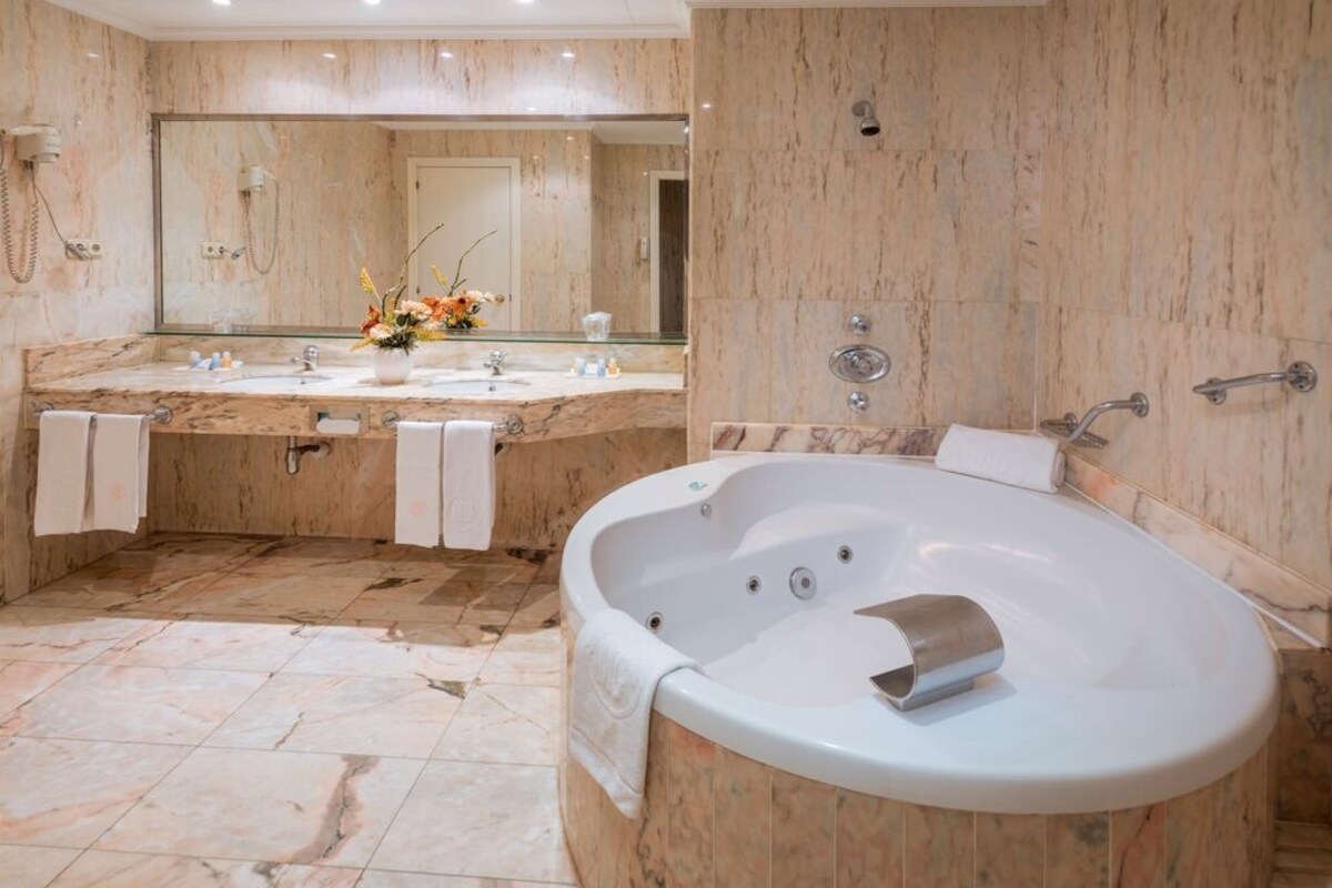 A modern bathroom with a large bathtub, a double sink vanity, and a large mirror.