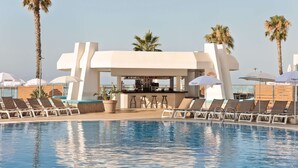 Un espace piscine avec des chaises longues et un bar.