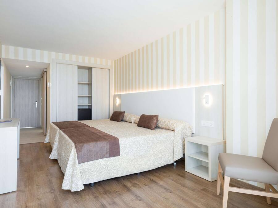 Un dormitorio con cama, mesitas de noche, una silla y televisión.