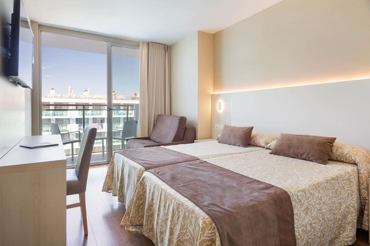 A hotel room with two beds, a desk, and a chair.
