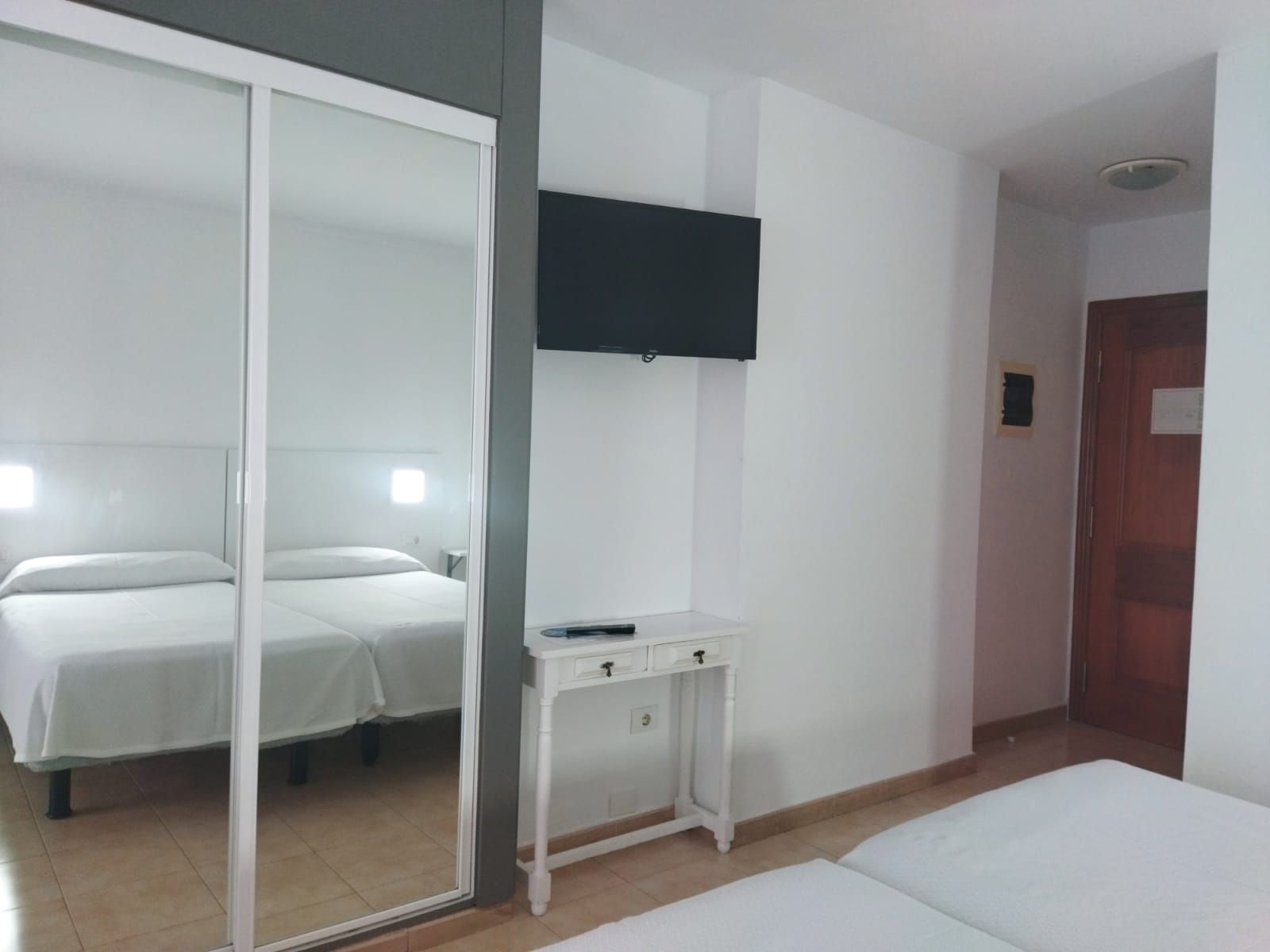 Une chambre d’hôtel avec un lit, un bureau, une télévision et une porte.
