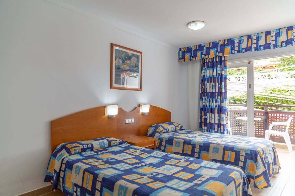 Une chambre d’hôtel avec deux lits, un tableau au mur et une vue sur l’extérieur.