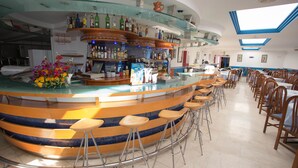 A bar area with stools, a counter, and a variety of bottles. There are tables and chairs in the dining area. - Pez Azul (Puerto de la Cruz)