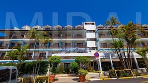 A multi-story hotel with balconies, palm trees, and a clear blue sky. - Pez Azul (Puerto de la Cruz)