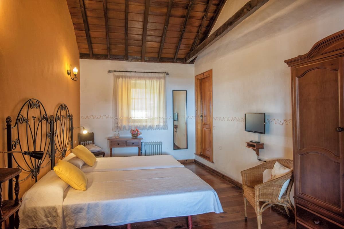 Une chambre à coucher avec un lit double, une table de chevet, une chaise, une télévision et une armoire.