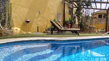 Una piscina al aire libre, sillones reclinables de piscina