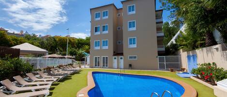 Una piscina al aire libre, sillones reclinables de piscina