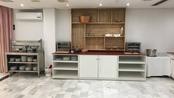 Una cocina con suelo de baldosas, electrodomésticos de acero inoxidable y estanterías de madera.