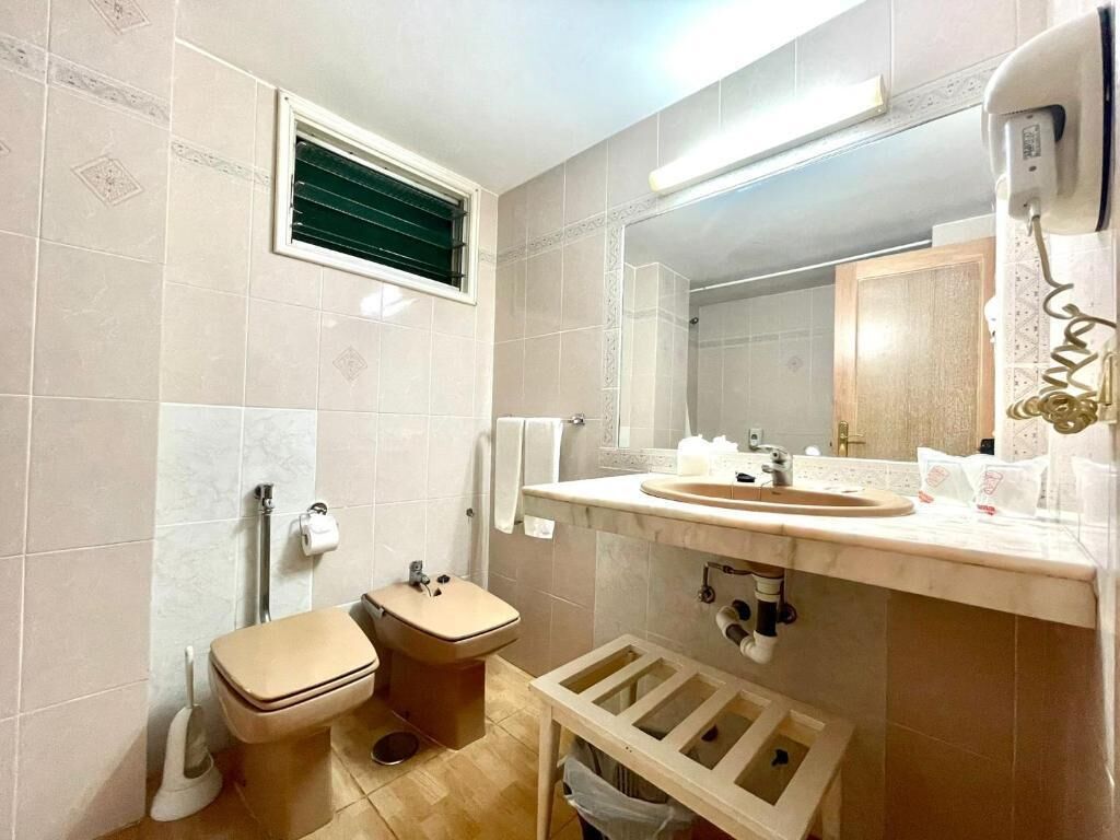 Un baño con inodoro, lavamanos, espejo y ducha.