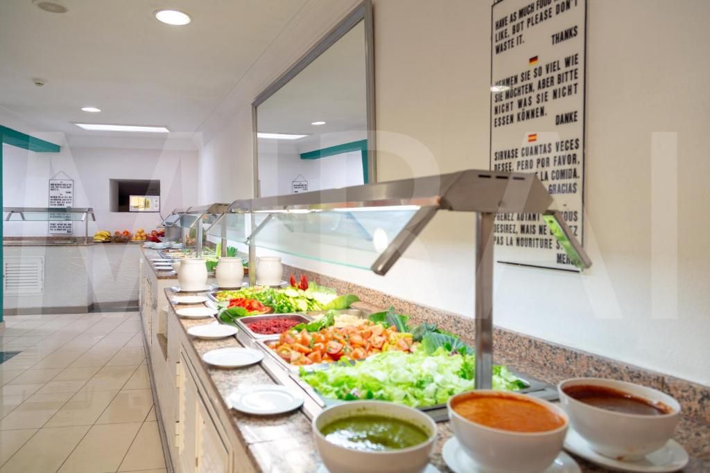 Uma área de buffet com diversas opções de comida e um letreiro com o cardápio.