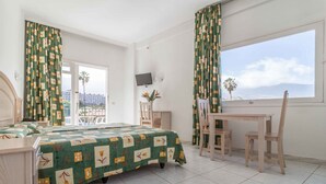 Ein Hotelzimmer mit Bett, Schreibtisch, Stuhl, Fernseher und einem Balkon mit Blick.