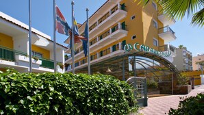 Ein Hotel mit gelber Fassade, mehreren Balkonen und einem überdachten Eingang.