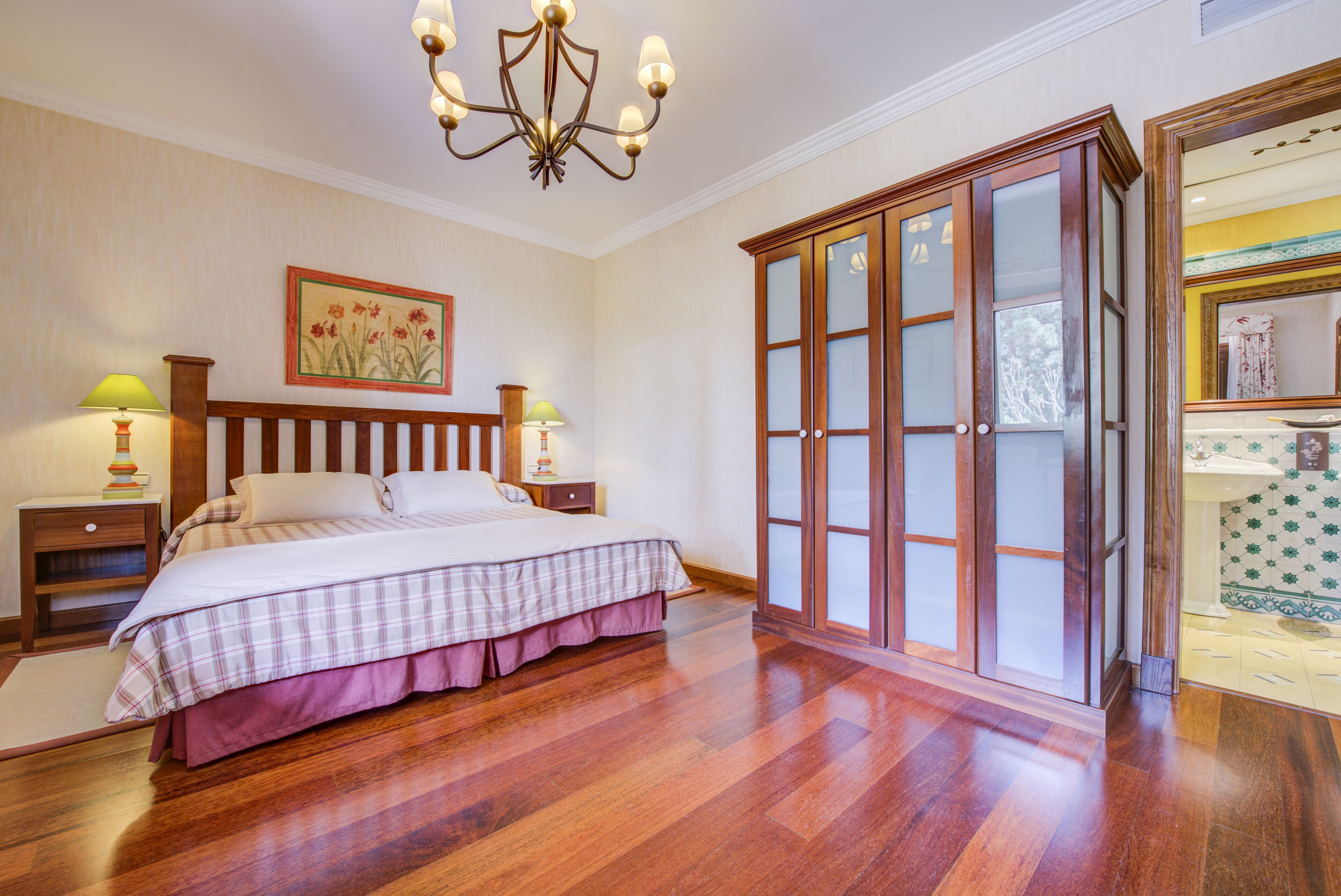 Une chambre à coucher avec un lit en bois, une table de chevet, une commode et un lustre.