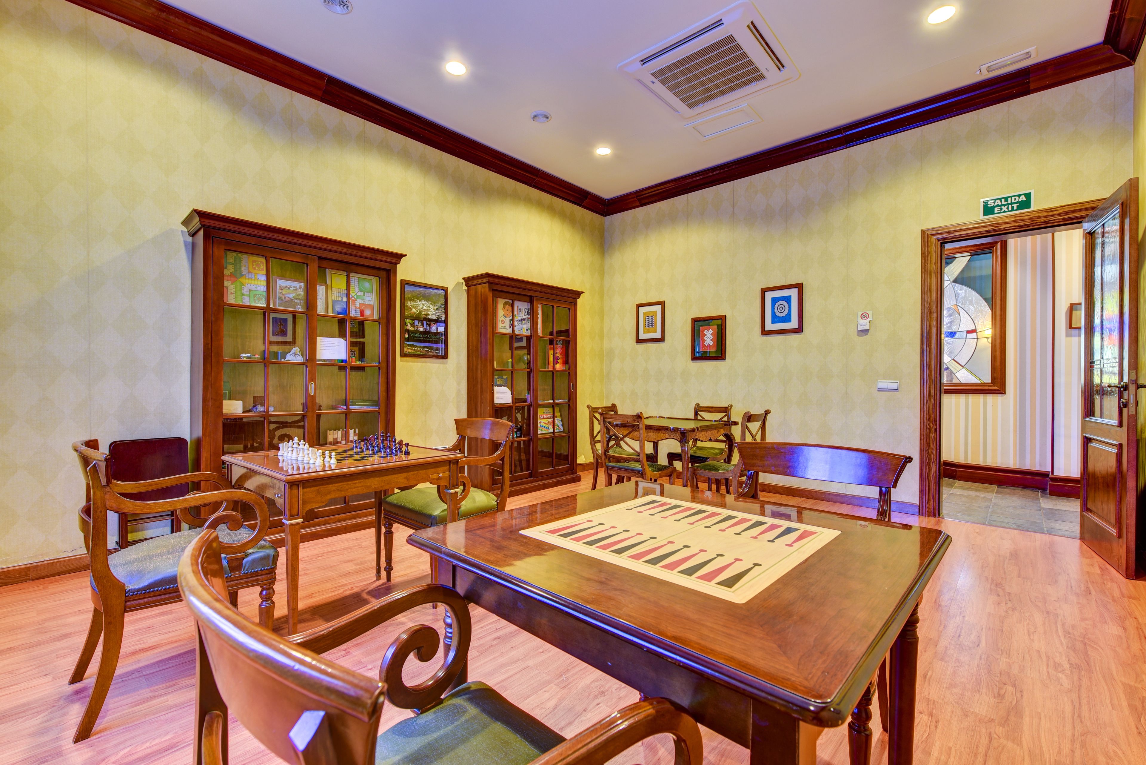 Una habitación con una mesa de madera, sillas, una estantería y una mesa de billar.