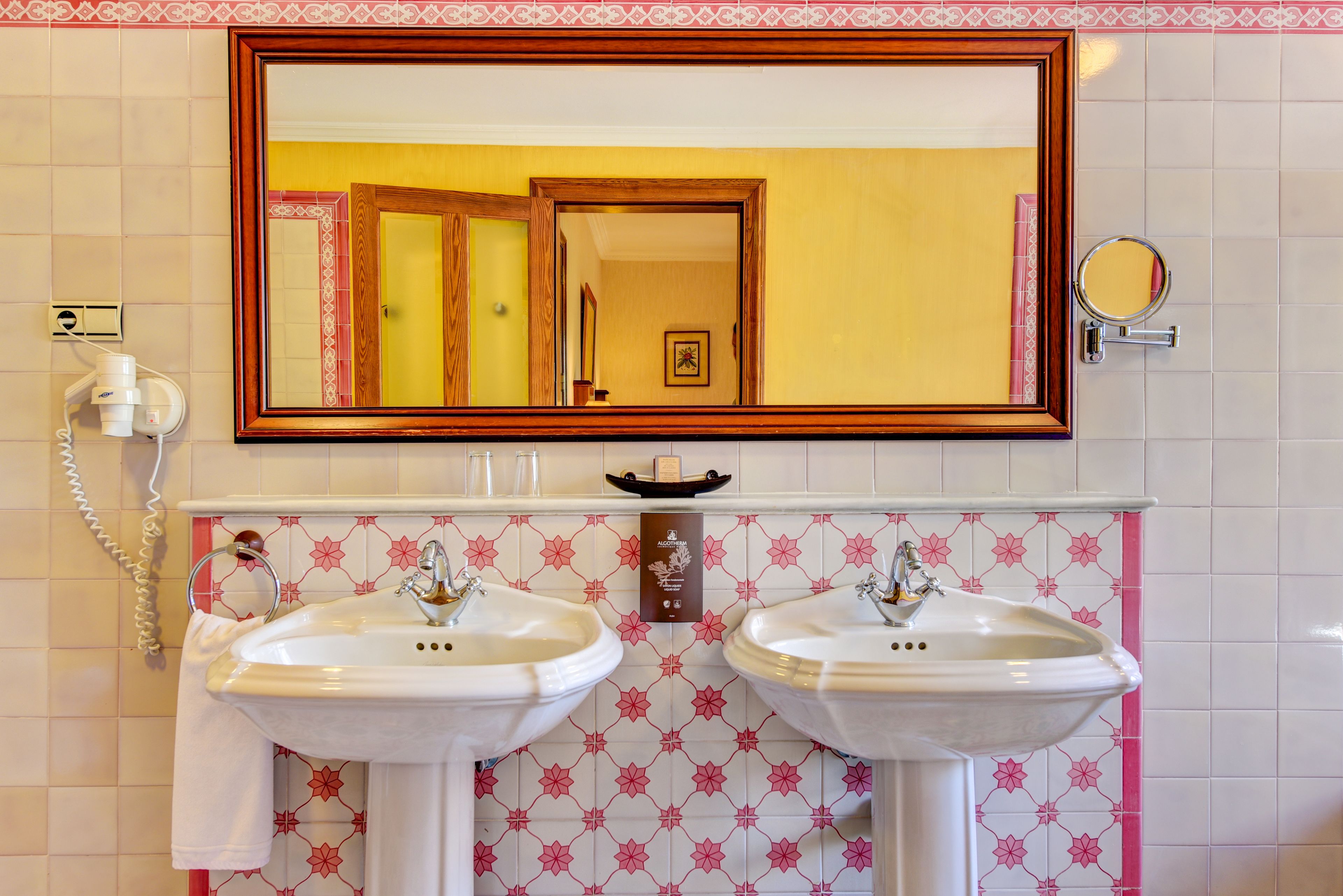 A bathroom with two white sinks, a large mirror, and a telephone.