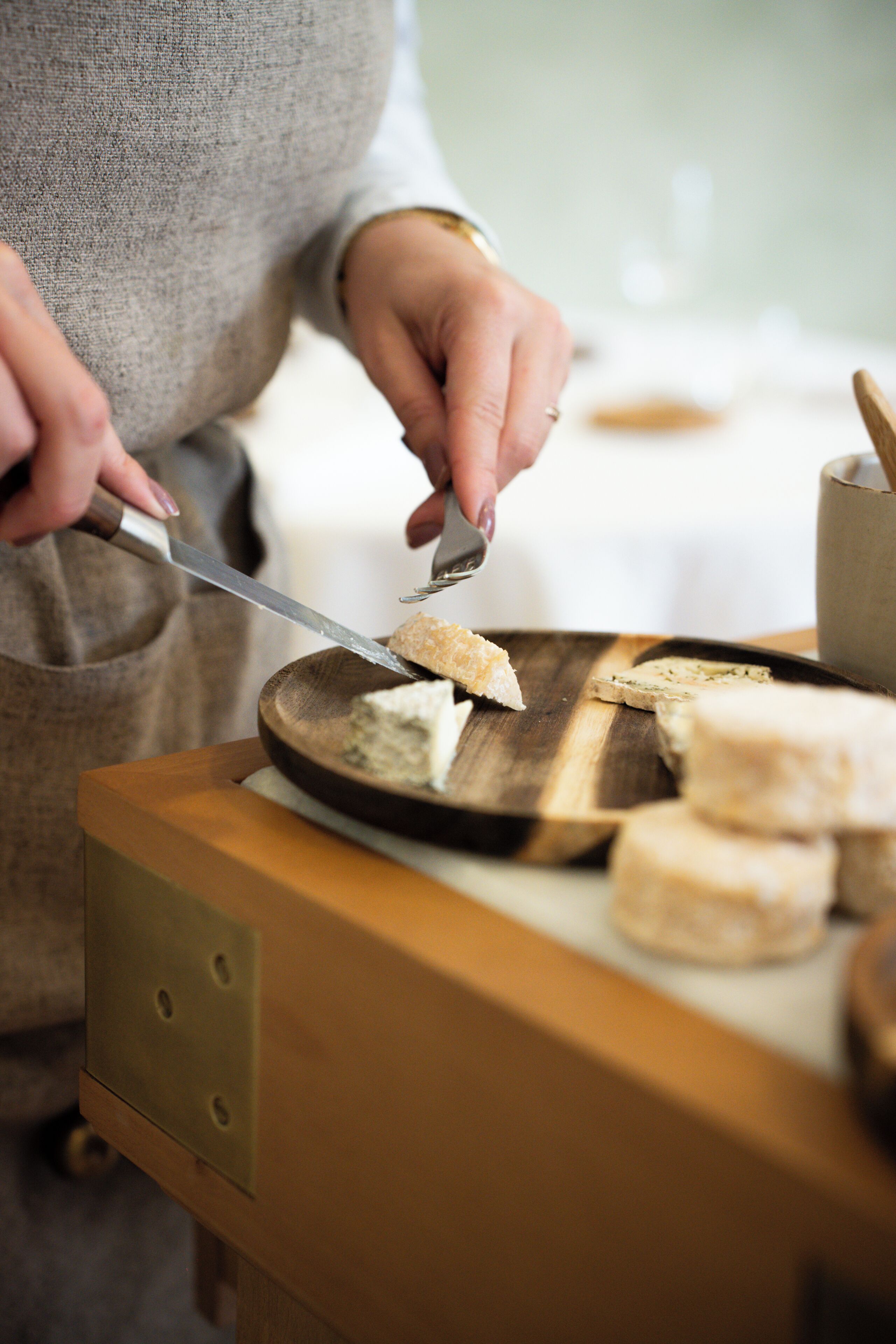 A person cutting cheese on a wooden board.