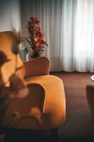 Um quarto com sofá, um vaso com flores e uma janela com cortinas.