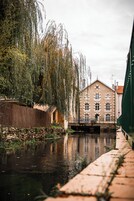 Um edifício com fachada de tijolos, parede de pedra e um canal com reflexos.