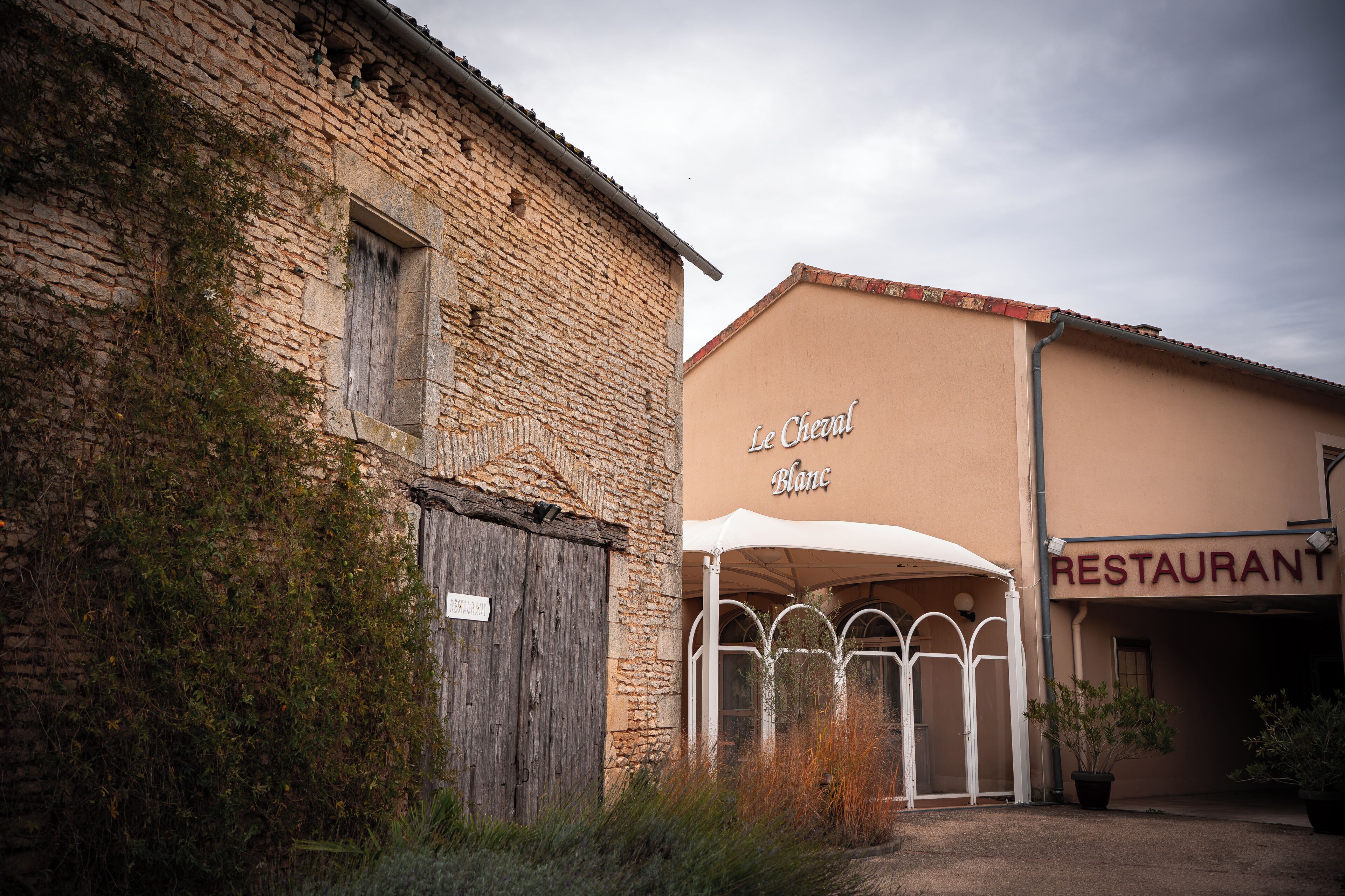 Un edificio con fachada de piedra y un letrero que dice 'Le Cheval Blanc'.