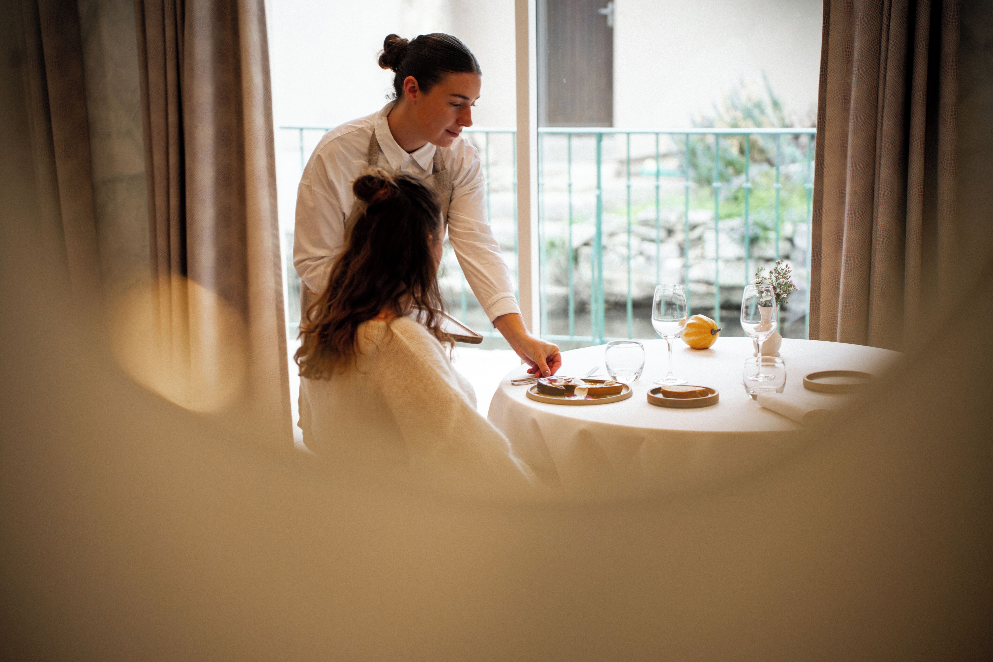 Une personne servant des plats à une table d’où l’on peut admirer la verdure environnante.