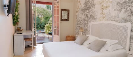 A bedroom with a bed, a desk, and a chair, a television, and a door leading to an outdoor area.