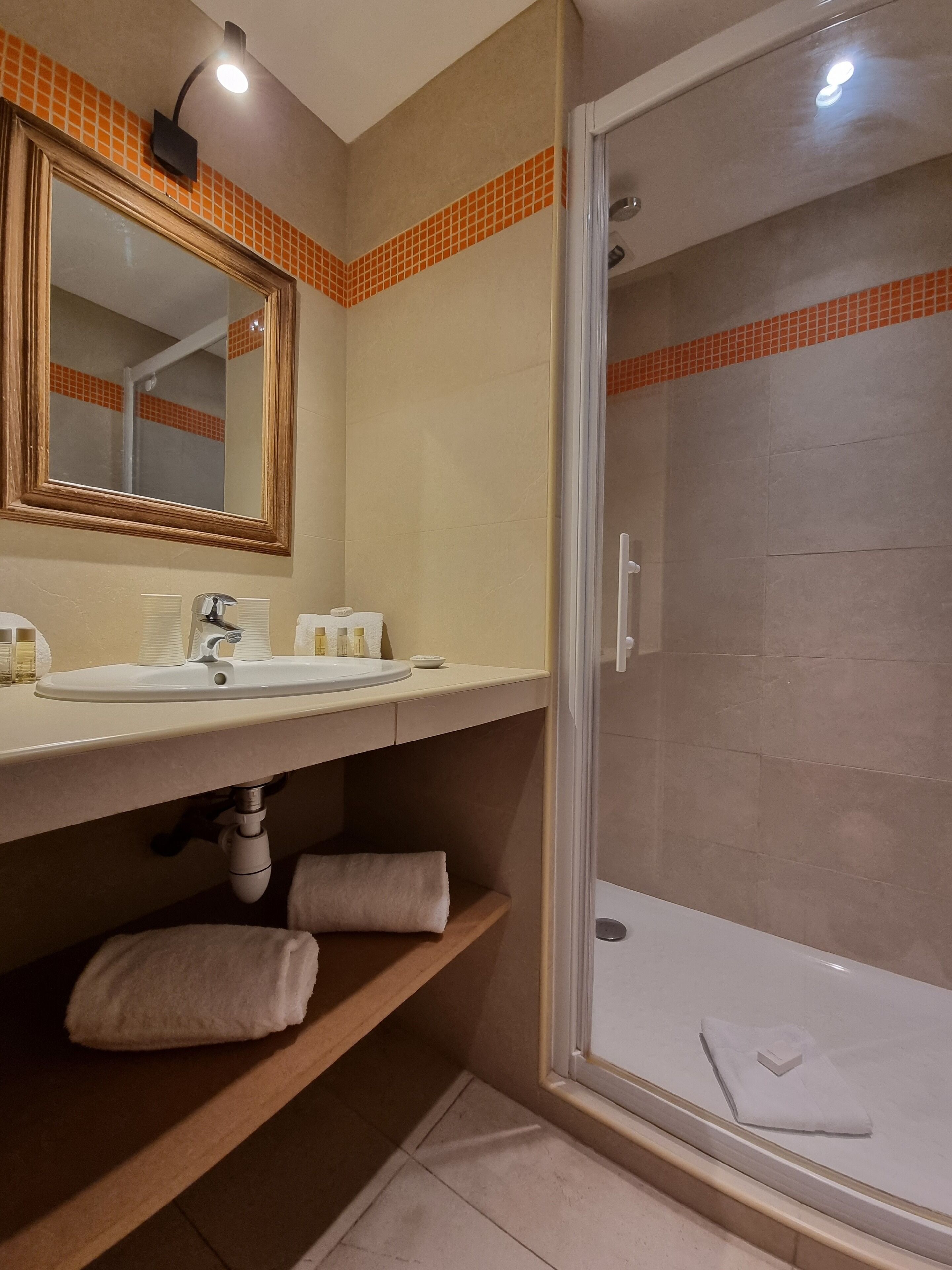 A bathroom with a sink, mirror, towel rack, and shower.
