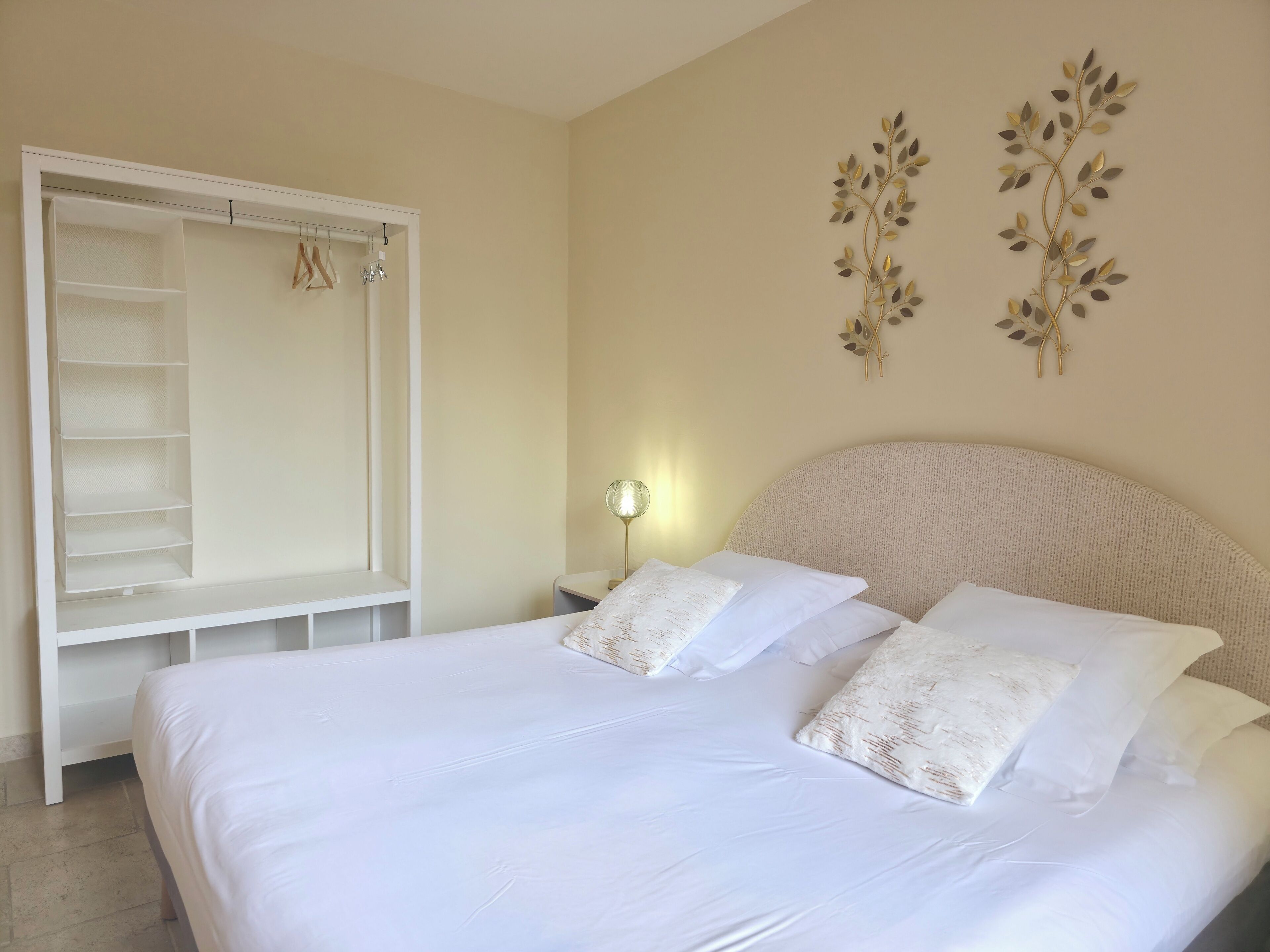 A bedroom with a bed, a wardrobe, a nightstand, and wall decor.