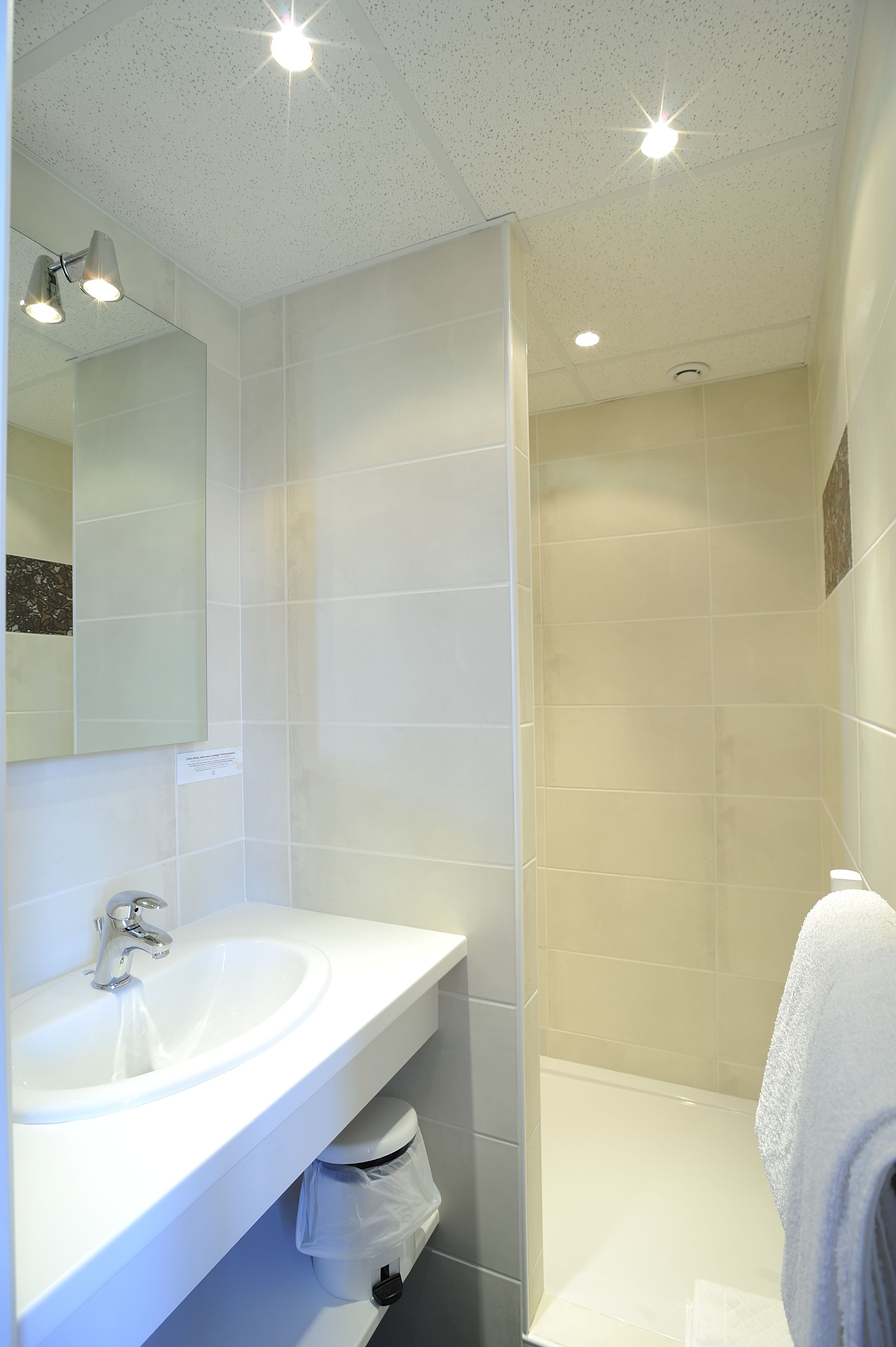 A modern bathroom with a white sink, mirror, and shower.